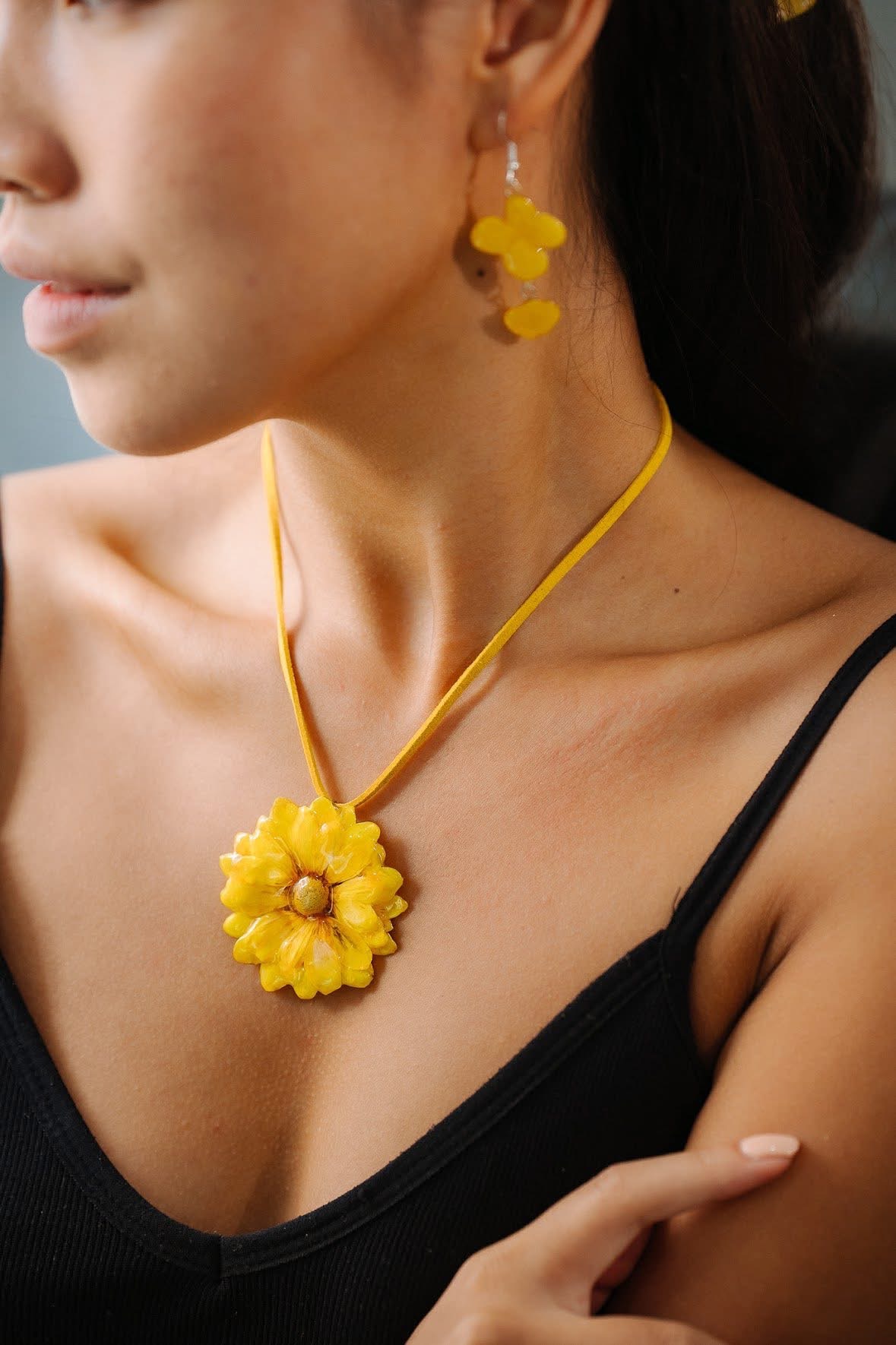Detail of yellow flower earrings and a pendant worn together